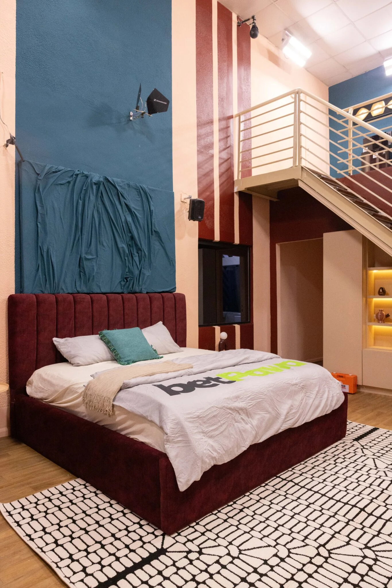 Luxury Head of House loft bedroom in the Big Brother Naija Season 11 house with a plush maroon bed and wooden mezzanine staircase. Credit: Multichoice